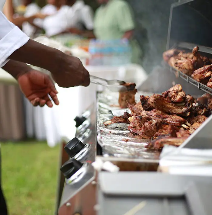 A person grilling meat on an outdoor grill.