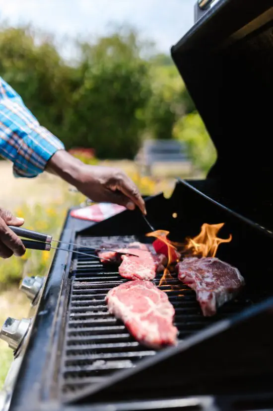 A person grilling meat on an outdoor grill.